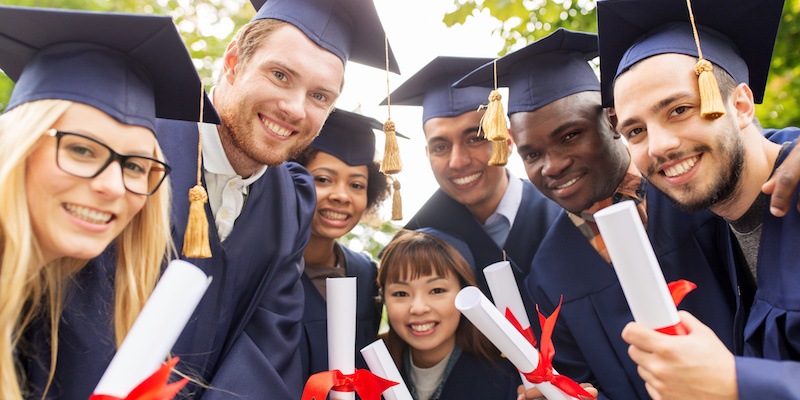 happy students in mortar boards with diplomas education, graduation and people concept - group of happy international students in mortar boards and bachelor gowns with diplomas